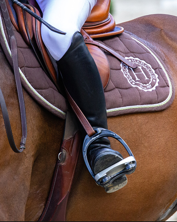 photographie d'un cavalier sur son cheval en gros plan sur la selle et la jambe du cavalier